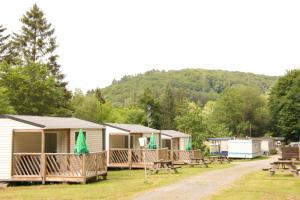 una fila de lodges con mesas de picnic y bancos en Cottage, 