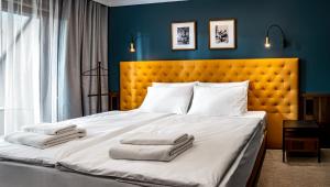 Palatinus Boutique Hotel في بيتْش: غرفة نوم بسرير كبير عليها منشفتين