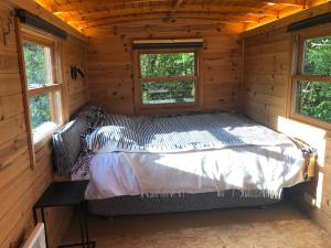 Bett in einem Blockhaus mit zwei Fenstern in der Unterkunft Cool de Sources in La Hulpe