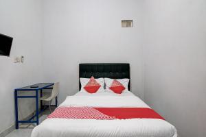 1 dormitorio con cama con almohadas rojas y escritorio en OYO 92111 Dinda Homestay Syariah en Dumai