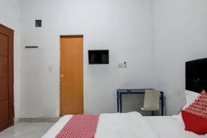 Schlafzimmer mit einem Bett, einem Tisch und einer Tür in der Unterkunft OYO 92111 Dinda Homestay Syariah in Dumai