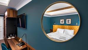 Palatinus Boutique Hotel في بيتْش: غرفة نوم مع مرآة على الجدار الأزرق