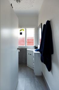 a white bathroom with a sink and a window at Art deco inner city comfort in Bendigo