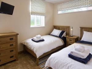 two twin beds in a room with a tv at Morton Grange Coach House - E5557 in Ellesmere