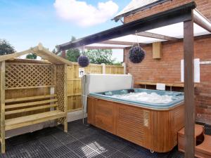 a hot tub on a patio with a pergola at Morton Grange Coach House - E5557 in Ellesmere