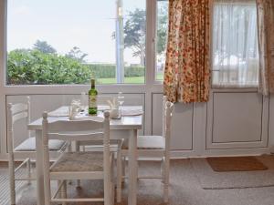 a white table and chairs with a bottle of wine at Brambles Cottage in Yarmouth
