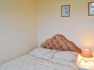 a bed with a tufted headboard in a bedroom at Brambles Cottage in Yarmouth