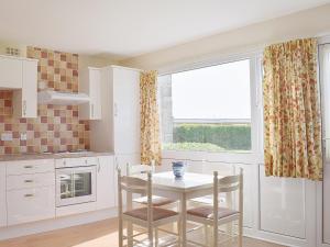 a kitchen with a table and chairs and a window at Brambles Cottage in Yarmouth