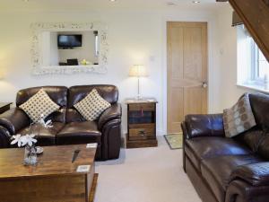 a living room with leather furniture and a mirror at Cherry Blossom Cottage in Birstwith