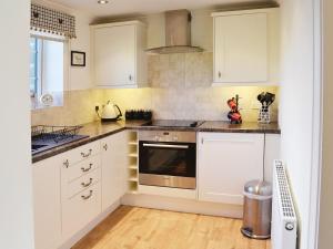 a kitchen with white cabinets and a stove top oven at Cherry Blossom Cottage in Birstwith