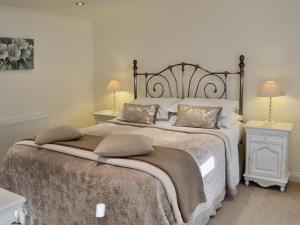 a bedroom with a large bed with two tables and two lamps at Cherry Blossom Cottage in Birstwith