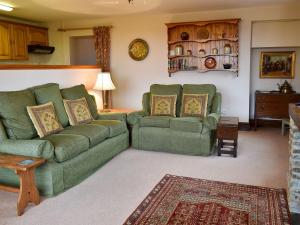 uma sala de estar com dois sofás verdes e uma mesa em Coach House em Loddiswell