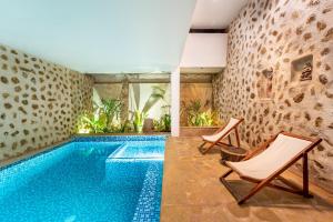 a swimming pool in a villa with two chairs at Conch Resort Luxury Private Pool Suites in Puducherry