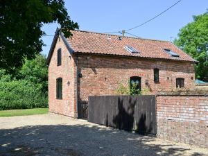 een oud bakstenen gebouw met een houten hek bij The Cottage in Great Ellingham