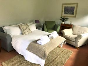 a living room with a bed and two chairs at Old Chapel Cottage in Dunster