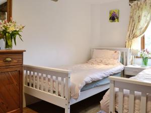 艾維布里奇的住宿－花園穀倉鄉村別墅，卧室配有2张白色婴儿床