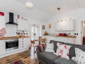 a living room with a couch and a kitchen at Ty Macsen in Llanwnda