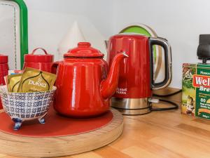 a red tea pot sitting on a counter next to a cup at Ty Macsen in Llanwnda