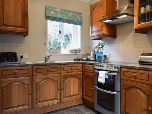 a kitchen with wooden cabinets and a sink and a window at The Coach House in Great Malvern