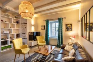 ein Wohnzimmer mit einem Ledersofa und gelben Stühlen in der Unterkunft Le Routhouan - Idéalement situé à Saint-Malo in Saint-Malo