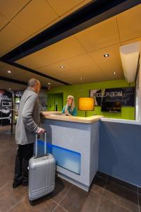 Een man met een koffer aan een balie op een vliegveld. bij ibis budget Albertville in Gilly-sur-Isère