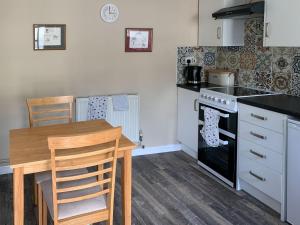 a kitchen with a table and a stove top oven at Orchard Bank Cottage in Longhope