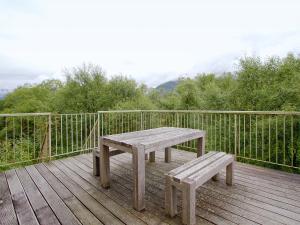 a wooden picnic table and bench on a deck at Carness West in North Ballachulish