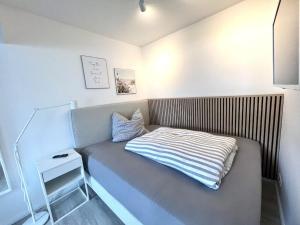 a small bed with a striped blanket on it at NEU! ERSTBEZUG! Vollsanierte Fewo mit Blick auf die Flensburger Förde in Harrislee