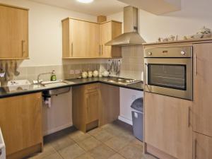 a kitchen with wooden cabinets and a stove top oven at The Coach House - Hw7593 in Bettws-yn-Rhôs