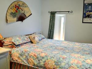 a bedroom with a bed with a floral comforter and a window at La Caleche in Cirencester