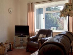 sala de estar con sofá de cuero y ventana en The Bungalow en Pentrich