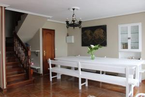 un comedor blanco con mesa blanca y bancos en Casa en Castanedo: Casa El Solarón, en Castanedo