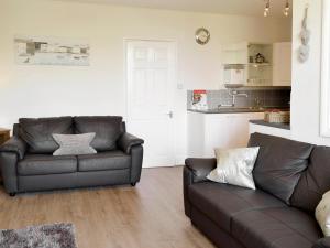 een woonkamer met 2 leren banken en een keuken bij St Martins Square Apartment 2 in Scarborough