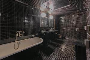 a black tiled bathroom with a tub and a sink at Sublime Suite à saint Germain des Près (Montana 7) in Paris