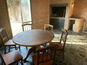 una mesa de madera y sillas en una habitación con chimenea en El Chulengo. en Luján de Cuyo