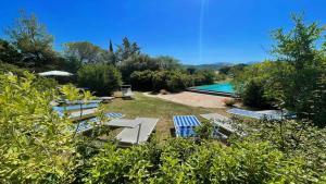 um quintal com uma piscina e cadeiras e um quintal com uma piscina em Exclusive pool - wondrous views - biological Gardens - pool house - 11 guests em Marzolini