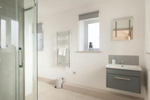 a white bathroom with a sink and a shower at The Dairy Parlour in Cricklade