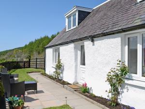 a white house with a patio and a yard at The Wee Hoose in Achnahanat