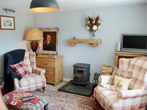 a living room with two chairs and a wood stove at The Wee Hoose in Achnahanat