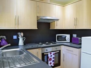 a kitchen with a sink and a stove top oven at Waulkmill Cottage in Carronbridge