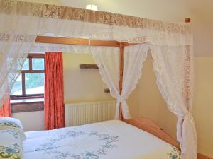 a bedroom with a canopy bed and a window at Robins Nest in Cromford