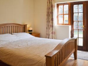 a bedroom with a large bed and a window at Rose Cottage - 30502 in West Firle