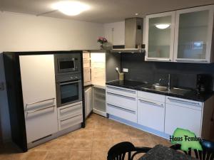 eine Küche mit weißen Geräten und einer schwarzen Arbeitsplatte in der Unterkunft Haus Fembre bis 4 Personen - 1 Hund erlaubt in Fehmarn