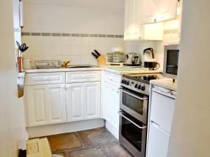 una cocina con armarios blancos y electrodomésticos blancos en Redmayne Cottage en Orton