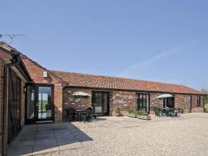 a brick building with tables and umbrellas on a patio at Russet Cottage - E4678 in Brean