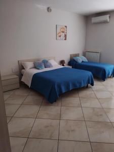 um quarto com 2 camas com lençóis azuis e piso em azulejo em SWEET HOME GIULIA Locazione ad uso turistico em Cimitile