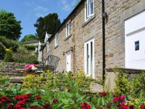 a row of brick houses with flowers in the foreground at Bank Cottage in Grindleford Bridge