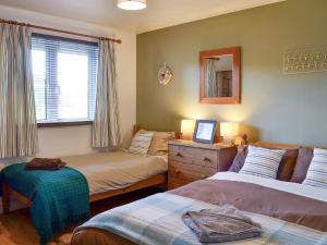 a bedroom with two beds and a mirror and a window at Honey Cottage in Auchnarrow