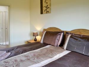 a bed with brown sheets and pillows in a bedroom at Buttercup Cottage in Ripley