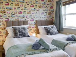 2 camas individuales en un dormitorio con papel pintado con coches en Signals Court, en Scarborough